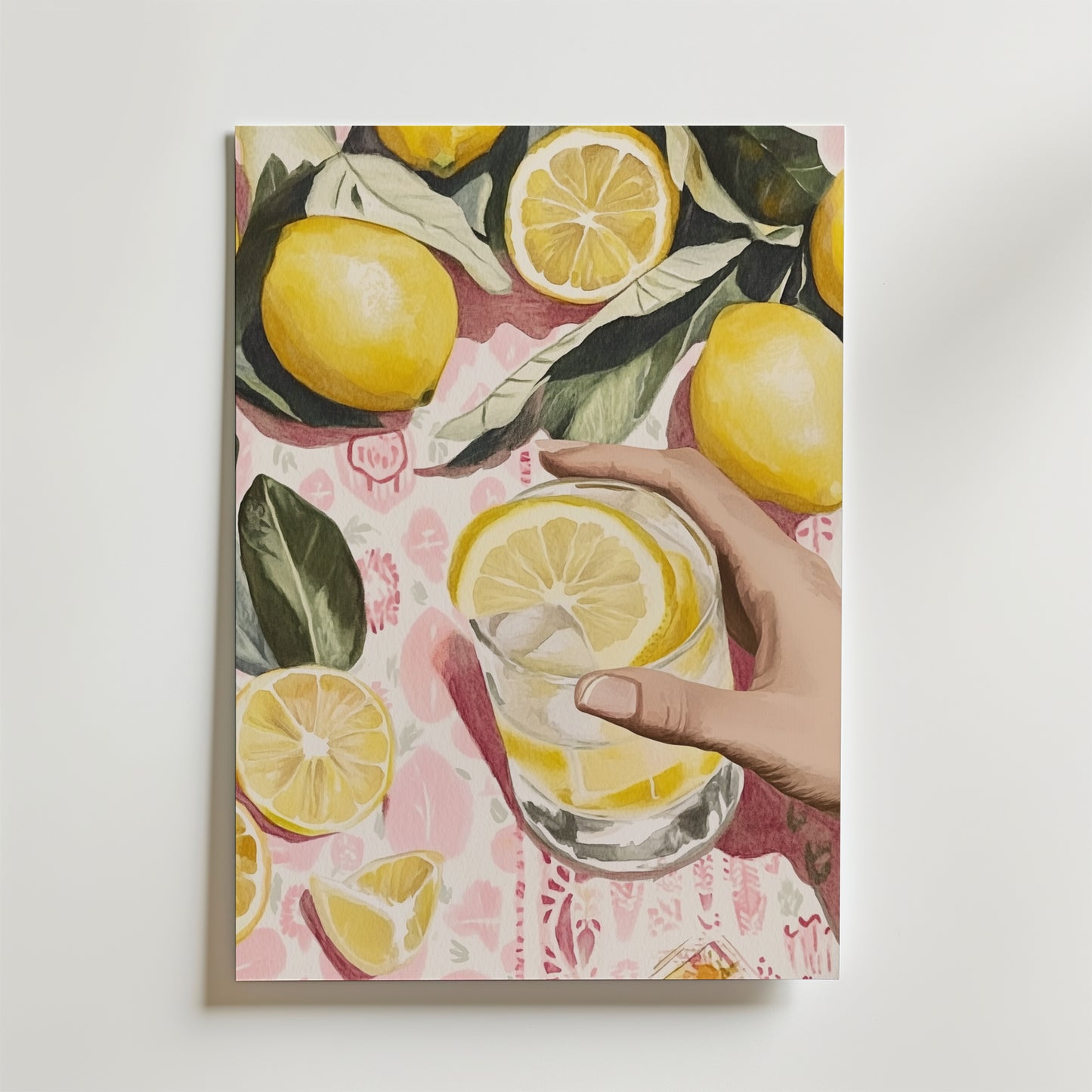 En hand håller i ett glas citronvatten på en rosa mönstrad yta med hela och skivade citroner. Lemon Delight Drink Poster by Bozetto är tryckt på premiumpapper och är FSC-certifierad för en miljövänlig stil.