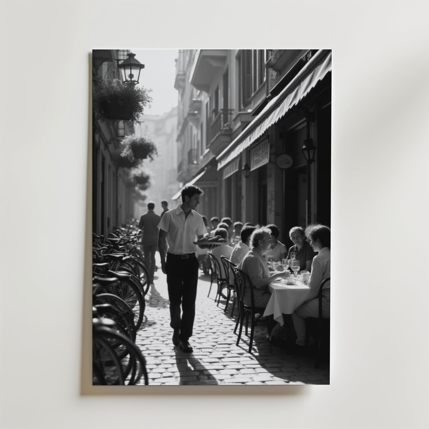 Charming Street Café Poster från Bozetto visar en svartvit scen av ett livligt utomhuscafé med gäster, en servitör och cyklar på en kullerstensgata - perfekt att visa på premiumpapper.