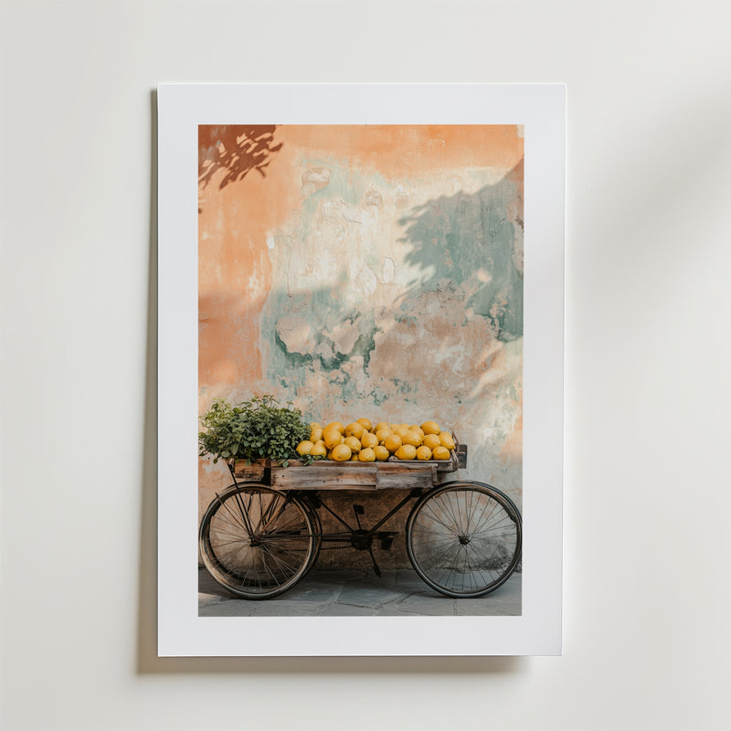 Wheels & Citrus Poster by Bozetto är ett inramat foto på FSC-certifierat premiumpapper som visar en vintage trävagn med citroner och en krukväxt, mot en väderbiten vägg i mjuka orange och gröna nyanser med högkvalitativ finish.
