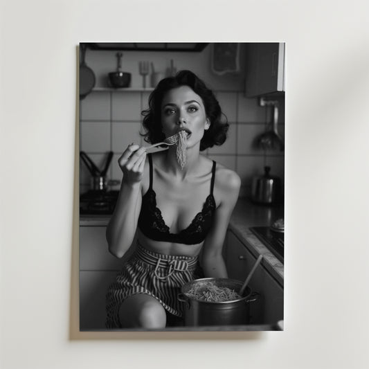 Ett svartvitt foto med en matt yta visar en kvinna i ett kök, klädd i en spetsbralette och randiga shorts, som äter nudlar från en kastrull. Denna Bozetto Spaghetti Vintage Poster framkallar retro charm för din inredning.