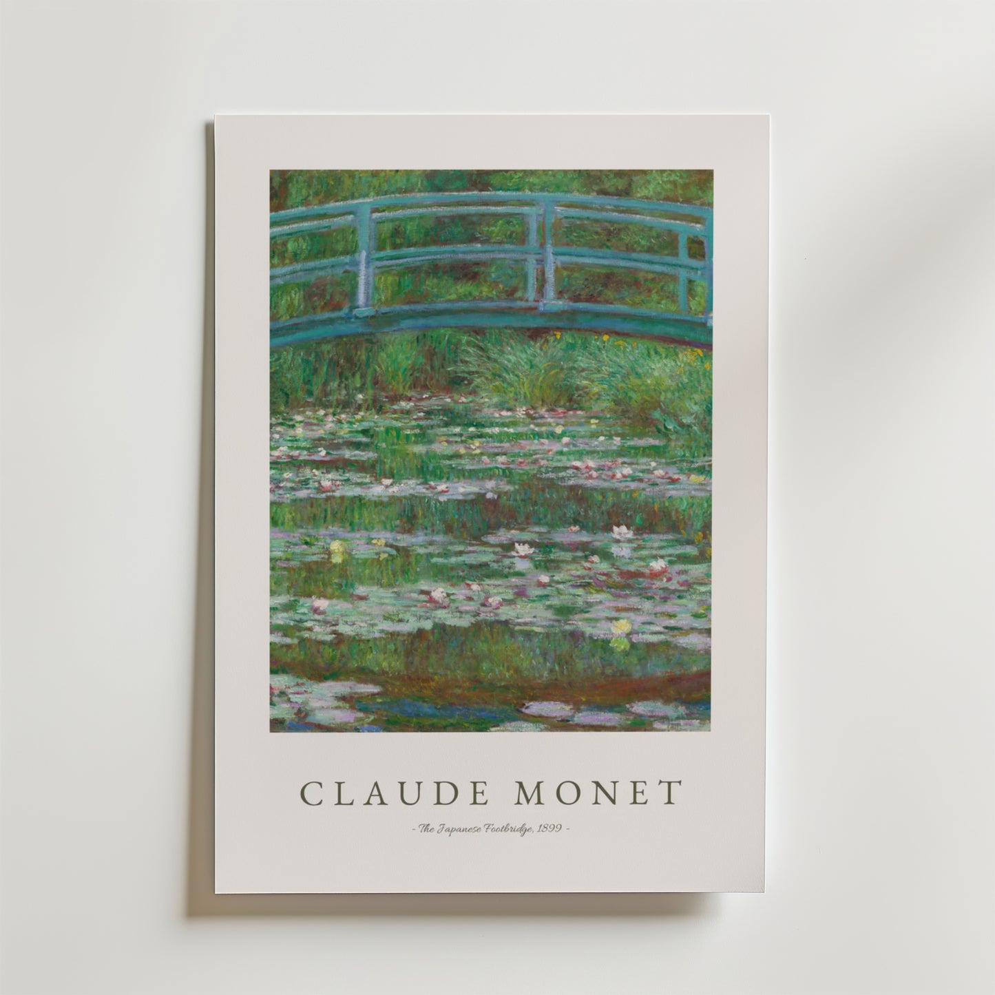Bozetto Claude Monet Footbridge Poster visar The Japanese Footbridge med en grön bågbro över en damm med rosa näckrosor, frodig grönska och har Monets namn och konstverkets titel nedan på premiumpapper.