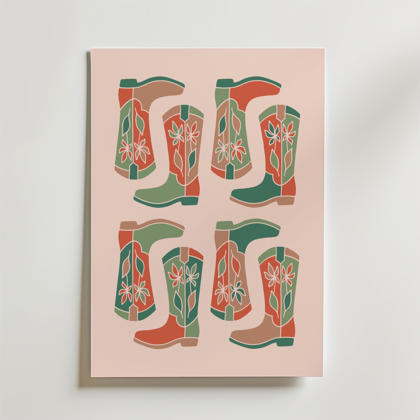 Boot Parade Poster by Bozetto har ett retro rutnätstryck av fyra par stiliserade cowboystövlar - sex stövlar - i grönt, rött och beige med enkla blommor på en ljusrosa bakgrund.