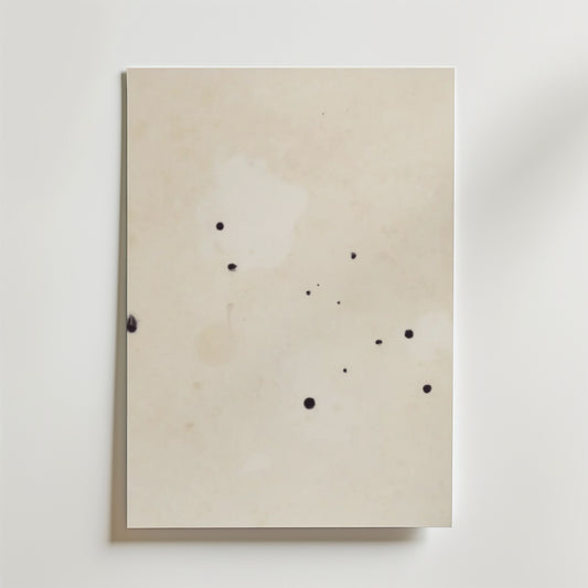 Postern Abstract Beige No.2 Poster by Bozetto har ett off-white premiumpapper med små, oregelbundna svarta bläckfläckar på den matta ytan, fotograferat mot en vit bakgrund.