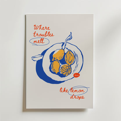 Postern Lemon Drops Poster by Bozetto föreställer en blå och gul illustrerad citron med röd handskriven text: "Där problem smälter som citrondroppar." Perfekt för dig som gillar unik, upplyftande inredning och handritade citroner.