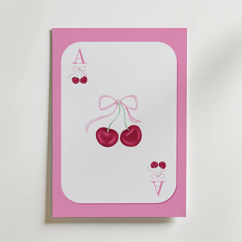 Ace of Cherries Poster by Bozetto föreställer ett spelkort med en rosa kant, två körsbär i mitten som är bundna med ett rosa band och små körsbär bredvid bokstäverna A och V i hörnen.